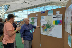 ME&A Lead Technology Solutions Strategist Benjamin White (right) explains to conference attendees GIS maps ME&A submitted on socioeconomic challenges facing the Mayan population in Guatemala.