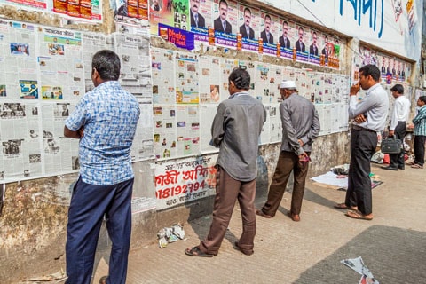 DHAKA, BANGLADESH - NOVEMBER 20, 2016: People are reading daily newspaper published on a wall in Dhaka, Bangladesh